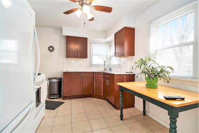 kitchen featuring light tile patterned floors, tasteful backsplash, ceiling fan, freestanding refrigerator, and a sink