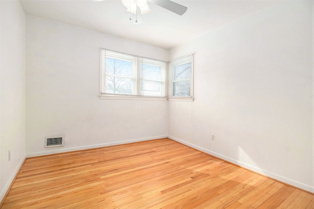 spare room featuring light wood-style floors, visible vents, ceiling fan, and baseboards