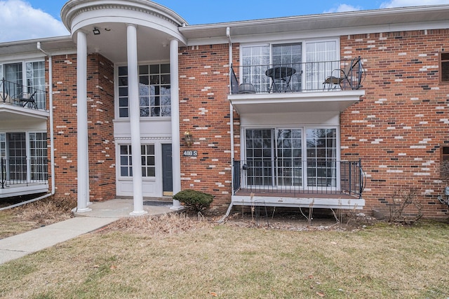 exterior space featuring a front yard, a balcony, and brick siding