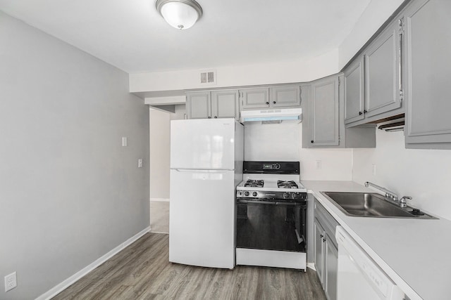 kitchen with white appliances, visible vents, gray cabinets, a sink, and under cabinet range hood