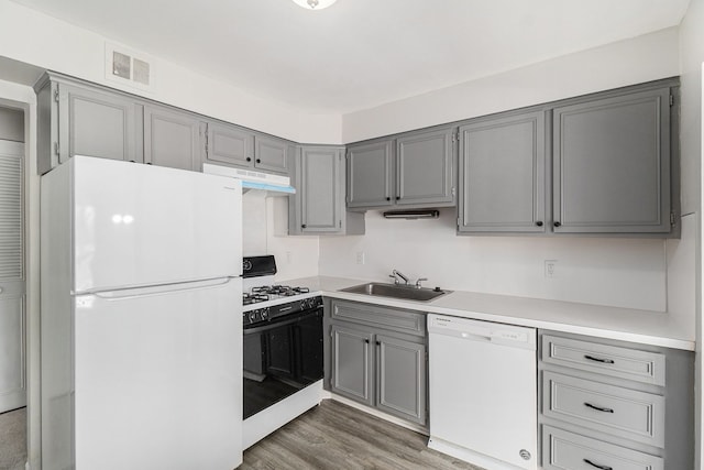 kitchen with white appliances, visible vents, gray cabinets, a sink, and under cabinet range hood