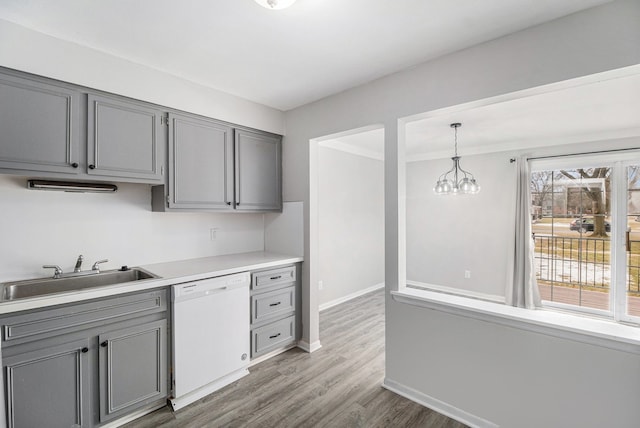 kitchen with dishwasher, wood finished floors, gray cabinets, and a sink