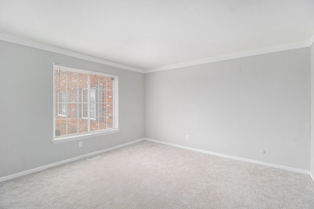 carpeted empty room with visible vents, baseboards, and crown molding