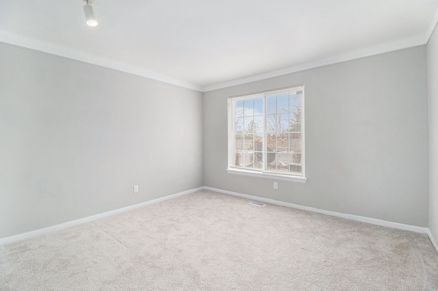 spare room with visible vents, ornamental molding, baseboards, and carpet floors