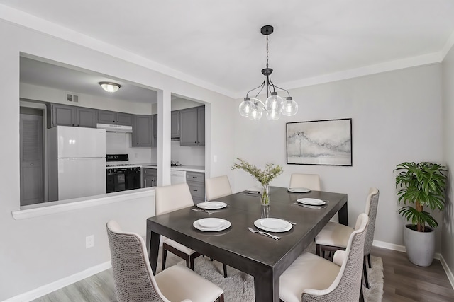 dining area with visible vents, baseboards, an inviting chandelier, and wood finished floors