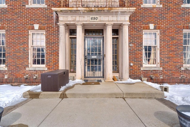 snow covered property entrance with brick siding