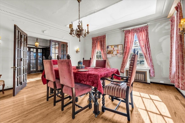 dining area with a notable chandelier, light wood-style floors, french doors, ornamental molding, and radiator heating unit