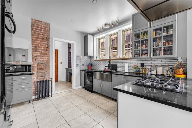 kitchen featuring decorative backsplash, gray cabinetry, glass insert cabinets, light tile patterned flooring, and black appliances