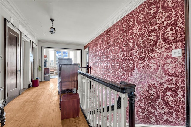 hallway featuring ornamental molding, light wood-type flooring, an upstairs landing, and wallpapered walls