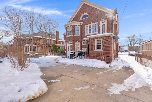 snow covered property featuring brick siding