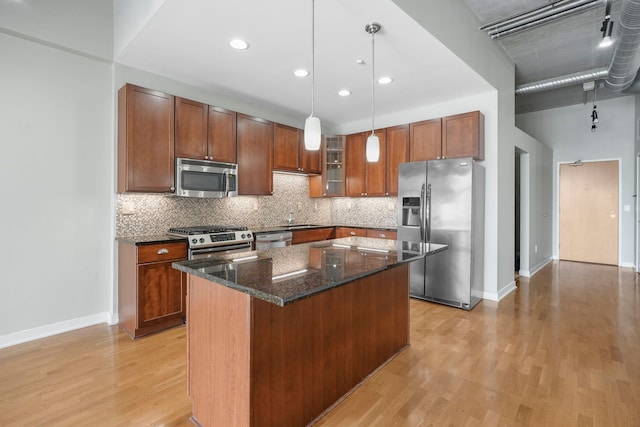 kitchen featuring stainless steel appliances, hanging light fixtures, a center island, dark stone countertops, and glass insert cabinets