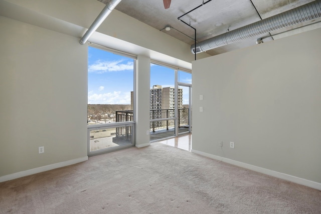 carpeted empty room featuring a city view and baseboards