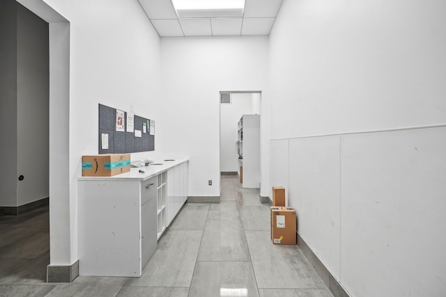 interior space featuring a paneled ceiling, light countertops, visible vents, and white cabinetry