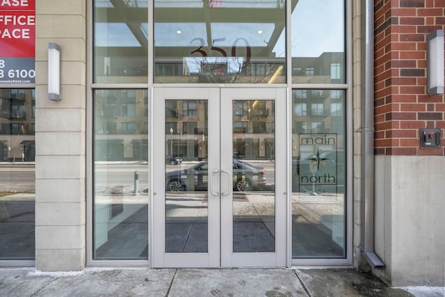 view of exterior entry featuring french doors and brick siding