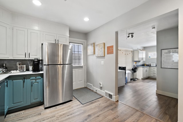 kitchen with white cabinets, visible vents, light countertops, and freestanding refrigerator