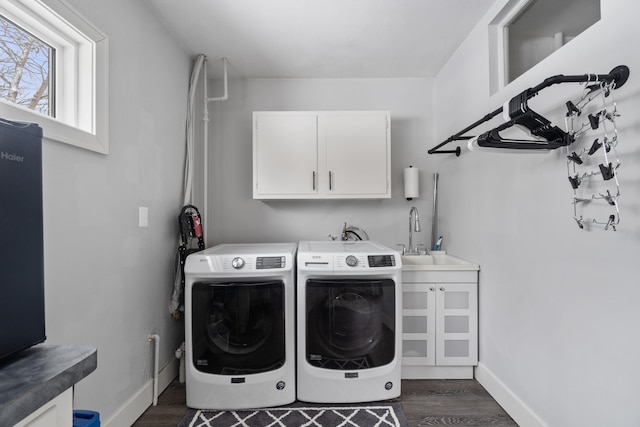 washroom featuring dark wood-style floors, washer and dryer, cabinet space, and a sink