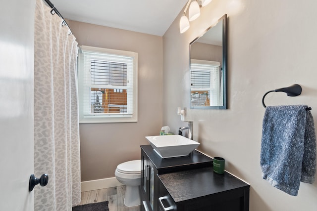 bathroom with toilet, wood finished floors, vanity, and baseboards