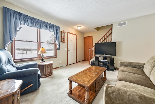 living room featuring stairs, a textured ceiling, visible vents, and light colored carpet