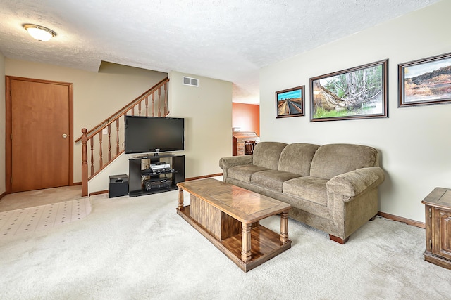 living room featuring light carpet, stairway, a textured ceiling, and visible vents