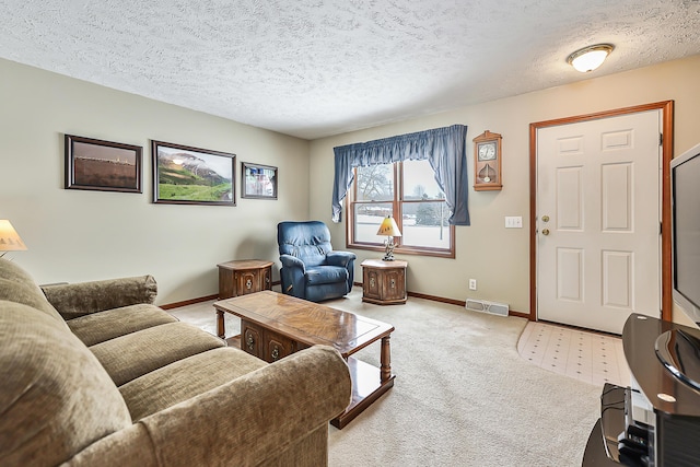 living area featuring baseboards, visible vents, and a textured ceiling