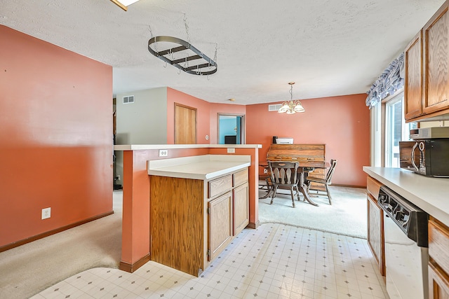 kitchen featuring visible vents, dishwasher, decorative light fixtures, light countertops, and light floors