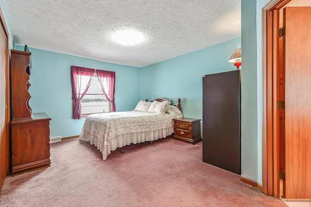 bedroom featuring a textured ceiling, carpet flooring, visible vents, and baseboards