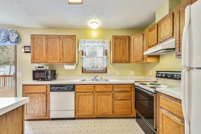 kitchen featuring white appliances, light floors, light countertops, under cabinet range hood, and a sink