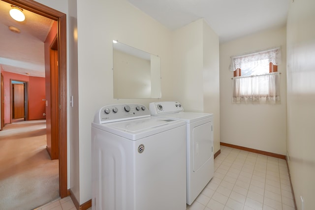 clothes washing area featuring washing machine and dryer, laundry area, light tile patterned flooring, and baseboards