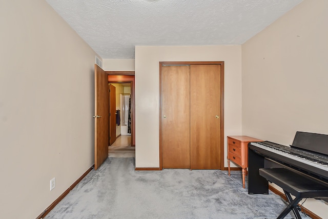 office featuring baseboards, a textured ceiling, visible vents, and light colored carpet