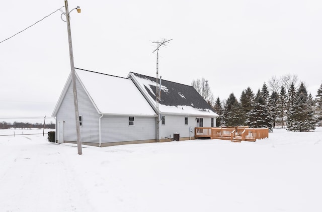 snow covered rear of property with a deck and central air condition unit