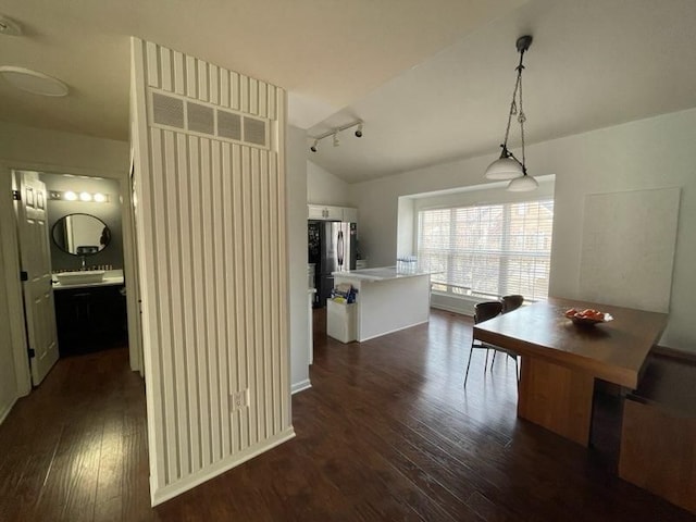 unfurnished dining area featuring dark wood-type flooring, lofted ceiling, and track lighting