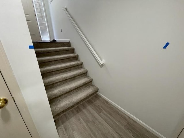 staircase featuring wood finished floors and baseboards