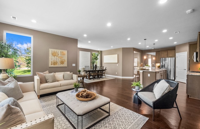 living area with dark wood-type flooring, plenty of natural light, visible vents, and recessed lighting