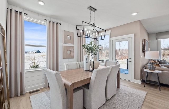 dining room with light wood finished floors, baseboards, visible vents, and a notable chandelier