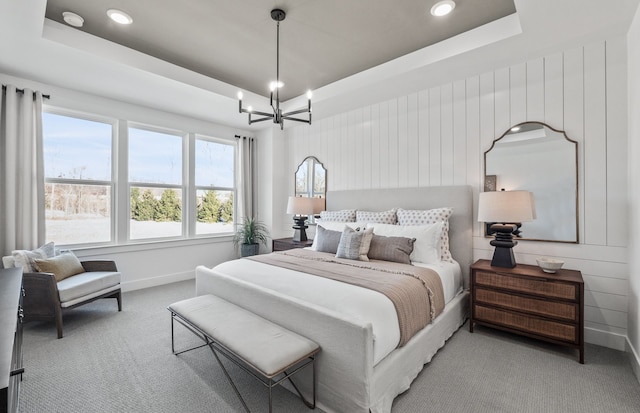 bedroom featuring a chandelier, a tray ceiling, light colored carpet, and baseboards