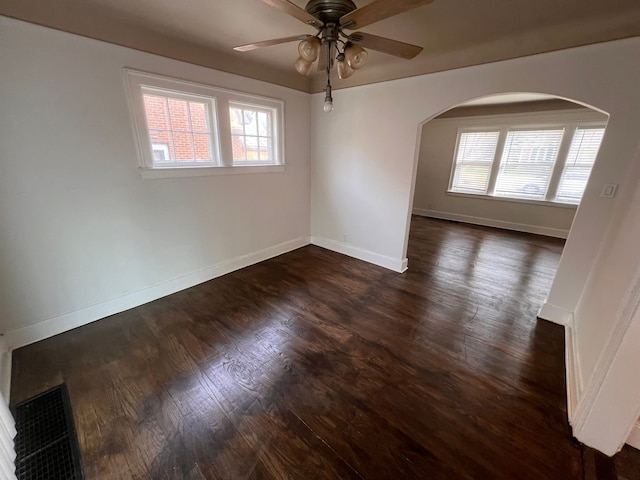 spare room featuring dark wood-style floors, a wealth of natural light, visible vents, and baseboards