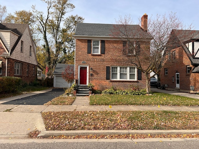 view of front of house with driveway, entry steps, a chimney, and brick siding