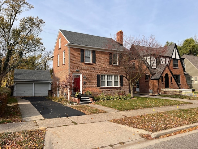 view of front of house featuring brick siding, an outdoor structure, a chimney, and a detached garage