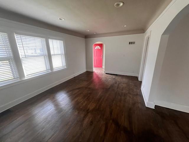 unfurnished room featuring arched walkways, recessed lighting, visible vents, dark wood-type flooring, and baseboards