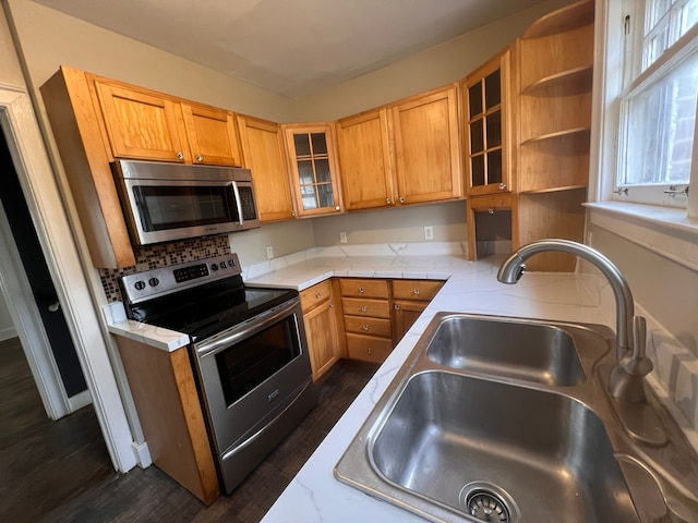 kitchen with open shelves, light countertops, appliances with stainless steel finishes, glass insert cabinets, and a sink