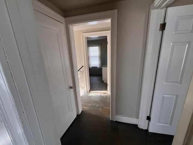 corridor featuring an upstairs landing, dark wood-style flooring, and baseboards