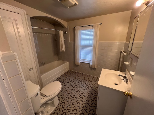 bathroom featuring toilet, a wainscoted wall, shower / tub combination, vanity, and tile walls