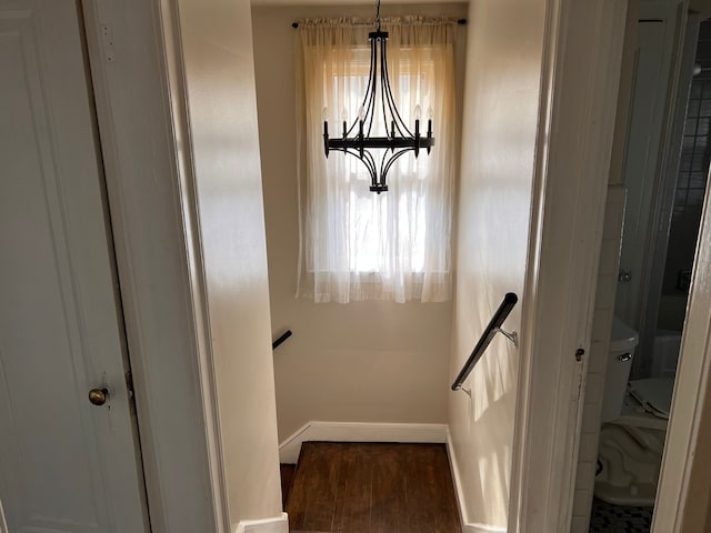 stairway featuring a chandelier, wood finished floors, and baseboards