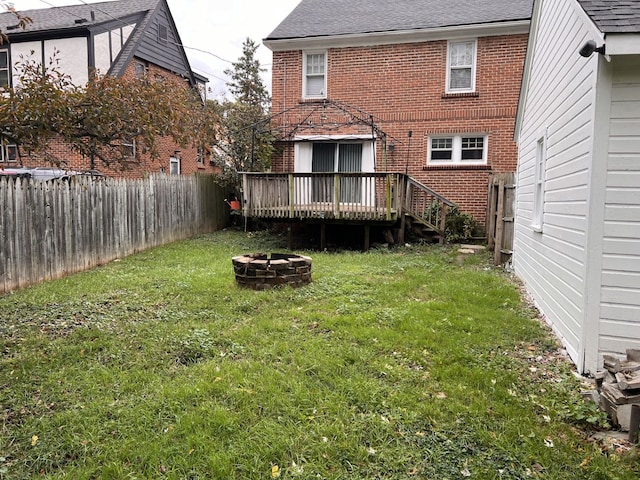 view of yard with a fenced backyard, a fire pit, and a deck