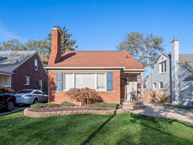 bungalow featuring brick siding, fence, a chimney, and a front lawn