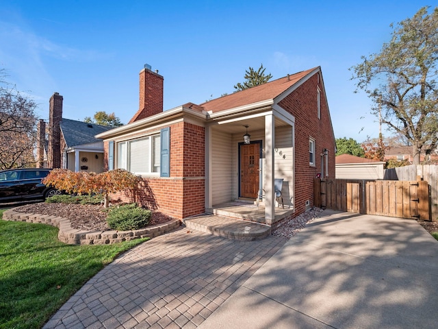 view of front of house featuring brick siding, fence, and a chimney