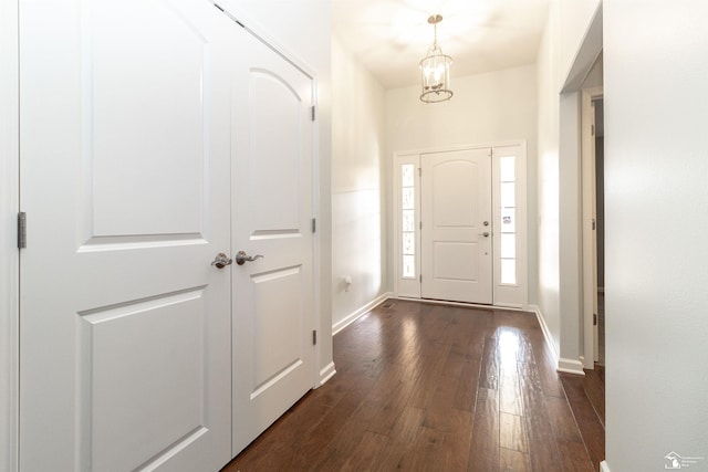 foyer featuring an inviting chandelier, baseboards, and dark wood-type flooring