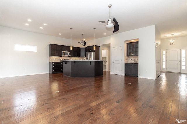 unfurnished living room with baseboards, dark wood-type flooring, ceiling fan with notable chandelier, a sink, and recessed lighting