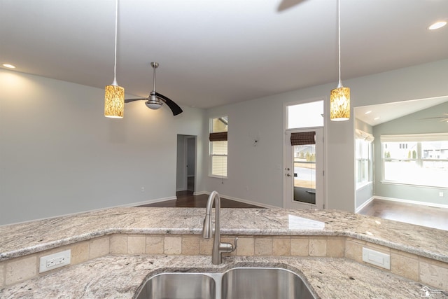 kitchen with light stone counters, recessed lighting, a ceiling fan, open floor plan, and a sink