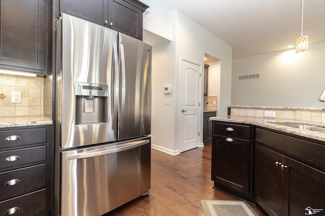 kitchen with tasteful backsplash, visible vents, dark wood-style flooring, stainless steel refrigerator with ice dispenser, and a sink